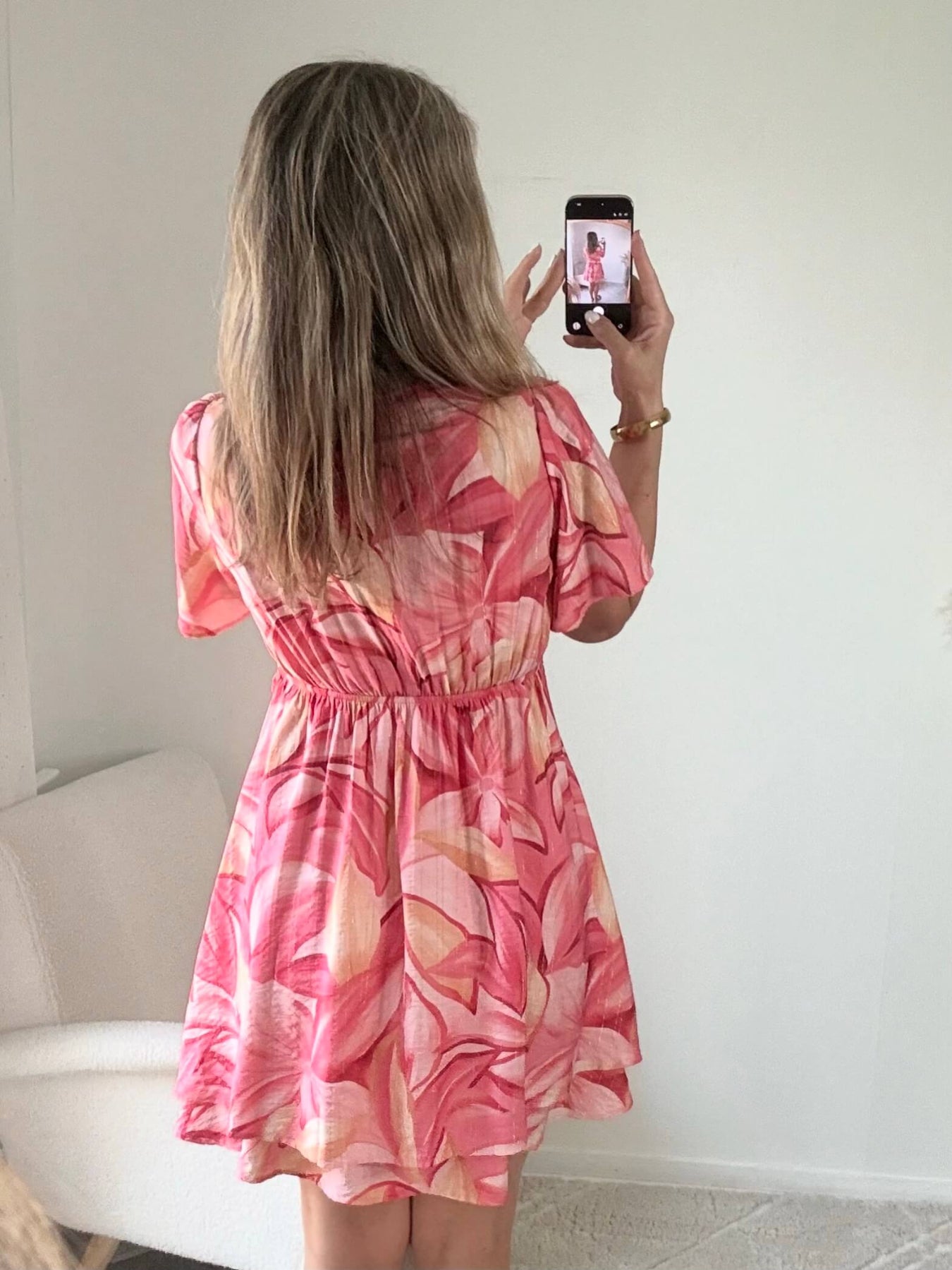 Robe Hany rose corail à imprimé floral, coupe courte fluide avec manches volantées, décolleté croisé et ceinture à nouer à la taille. Disponible du S au 4XL.