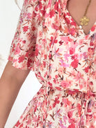 Robe courte corail fleurie Lyséa à manches courtes volantées et taille élastiquée, portée par un mannequin dans un intérieur lumineux.