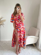 Robe longue imprimé tropical rose fuchsia, corail et bleu avec manches courtes et décolleté cache-cœur.
