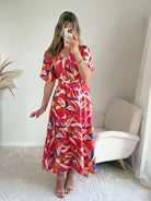 Robe longue imprimé tropical rose fuchsia, corail et bleu avec manches courtes et décolleté cache-cœur.