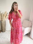 Robe longue Scarlett imprimée rose coupe fluide avec décolleté en V et manches courtes.