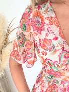 Robe longue Jasmine à imprimé floral rose et corail avec décolleté en V et manches fluides.