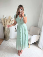 Robe Madison longue fluide à volants avec décolleté cache-cœur et manches volantées, disponible en vert d’eau, rose poudré et fuchsia, taille unique du 36 au 42.